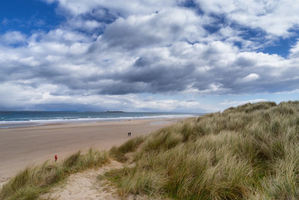 Rozlehlá písečná pláž pod hradem Bamburgh.