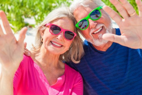 Usměvavý pár aktivních cestovatelů 55+ těšící se na poznávací zájezd do USA a Kanady.