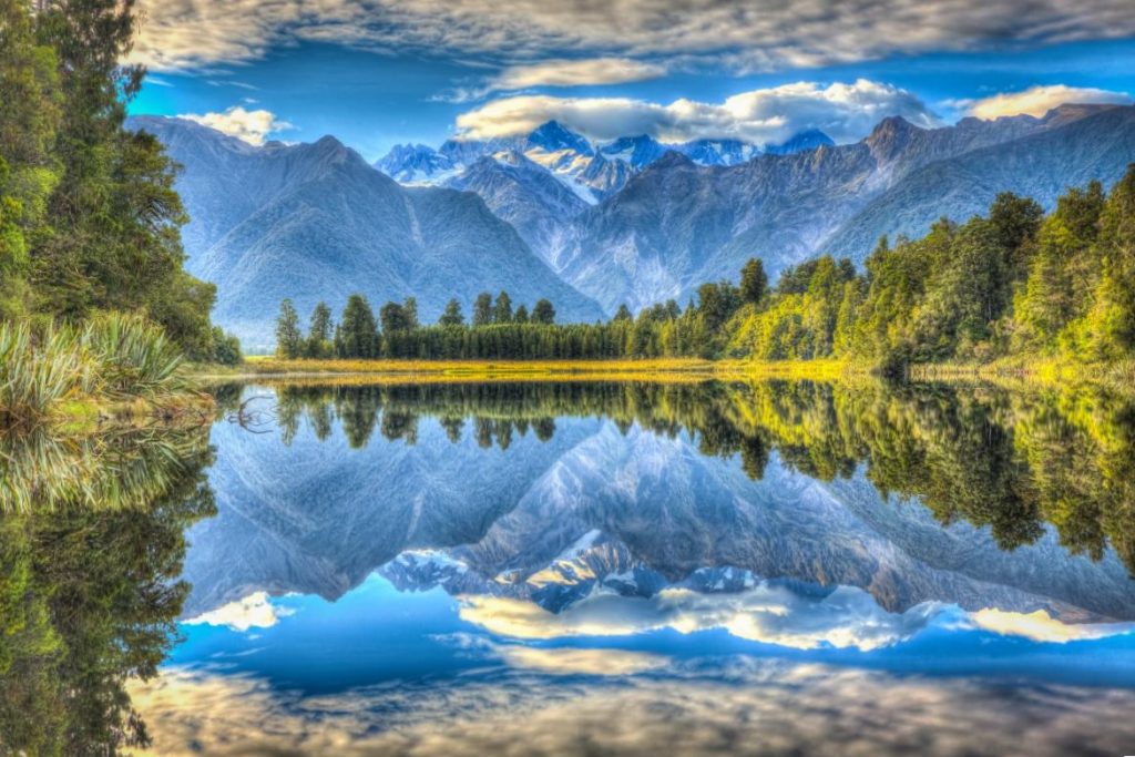 Okolní hory a lesy zrcadlící se v klidné hladině jezera Matheson lake.