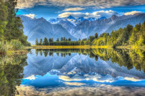 Okolní hory a lesy zrcadlící se v klidné hladině jezera Matheson lake.