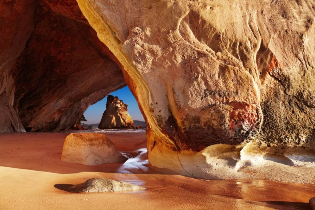 Přírodní skalní oblouk na břehu moře v Cathedral Cove