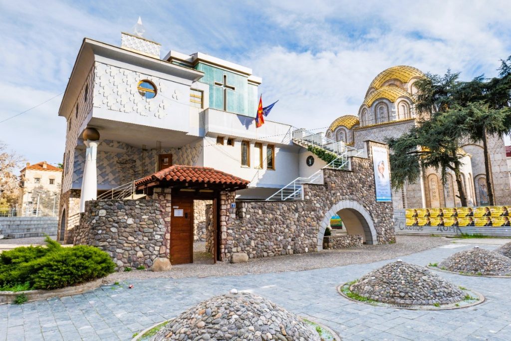 Moderní budova Památného domu Matky Terezy, kde se nachází muzeum věnované jejímu odkazu, s volně přístupnou prosklenou kaplí.