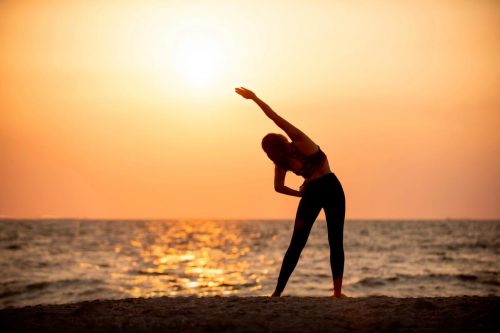 Žena cvičící jógu na břehu moře.