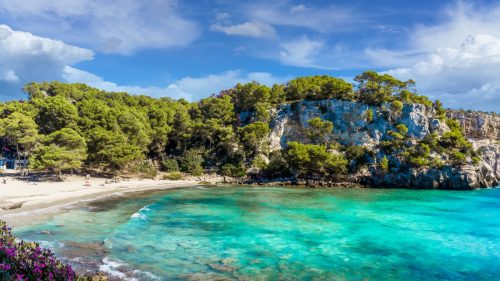 Cala Macarella s tyrkysovým mořem a borovicemi na jižním pobřeží Menorky.